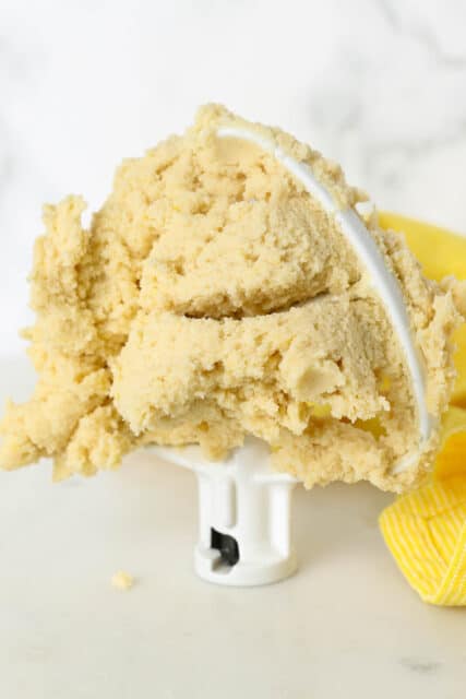 Lemon cookie dough stuck to a stand mixer attachment, propped upright.