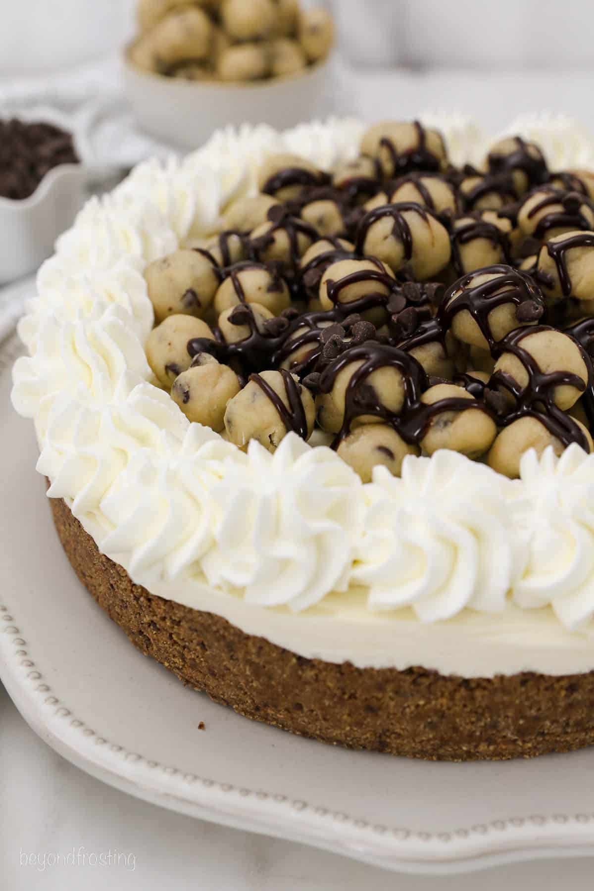 overhead of a whole cookie dough cheesecake piled with cookie dough balls and topped with whipped cream.
