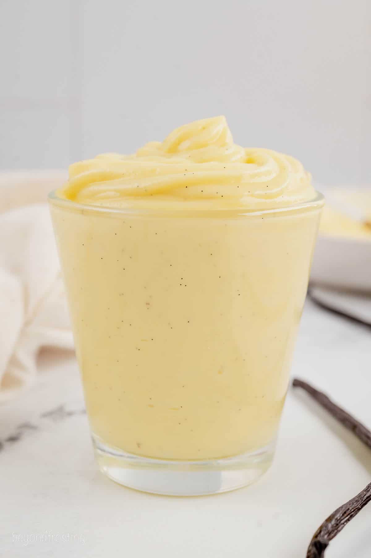 A glass of homemade pastry cream on a countertop.