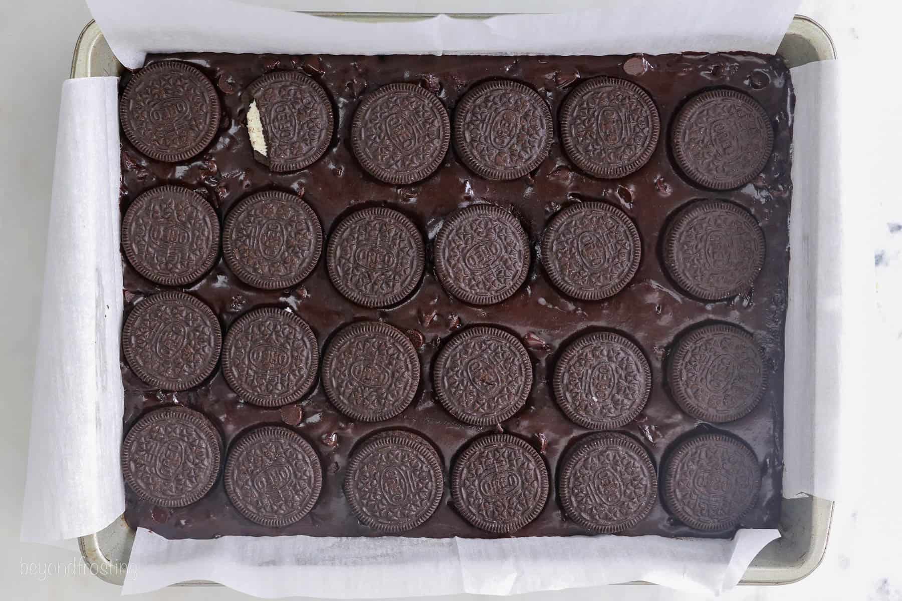 Oreos layered overtop of the brownie batter in a large baking pan.