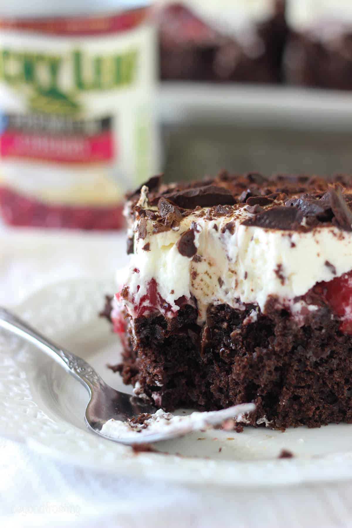 a slice of black forest cake with a bite taken out on a plate.