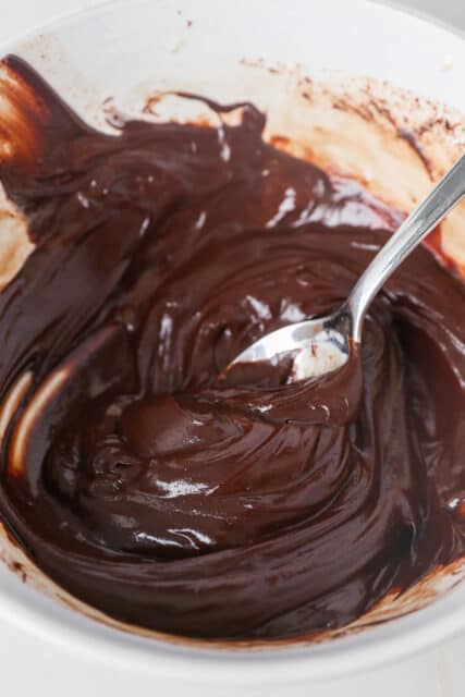 Melted chocolate ganache in a bowl with a spoon