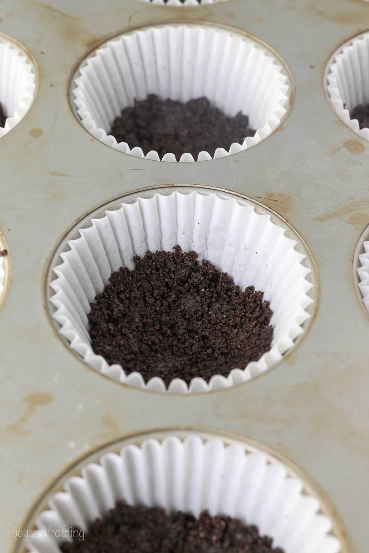 a cupcake pan, lined with paper cups and filled with an Oreo crust
