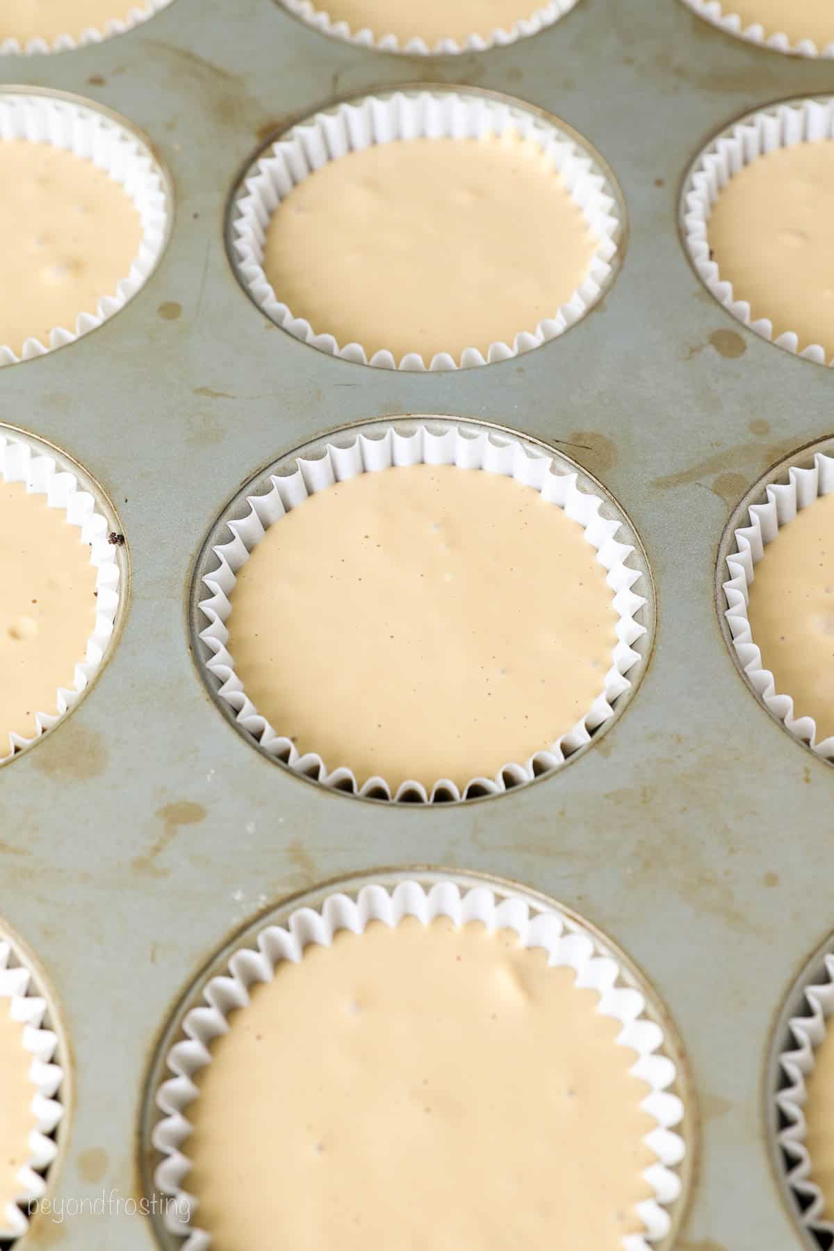 A cupcake pan filled with coffee cheesecake batter