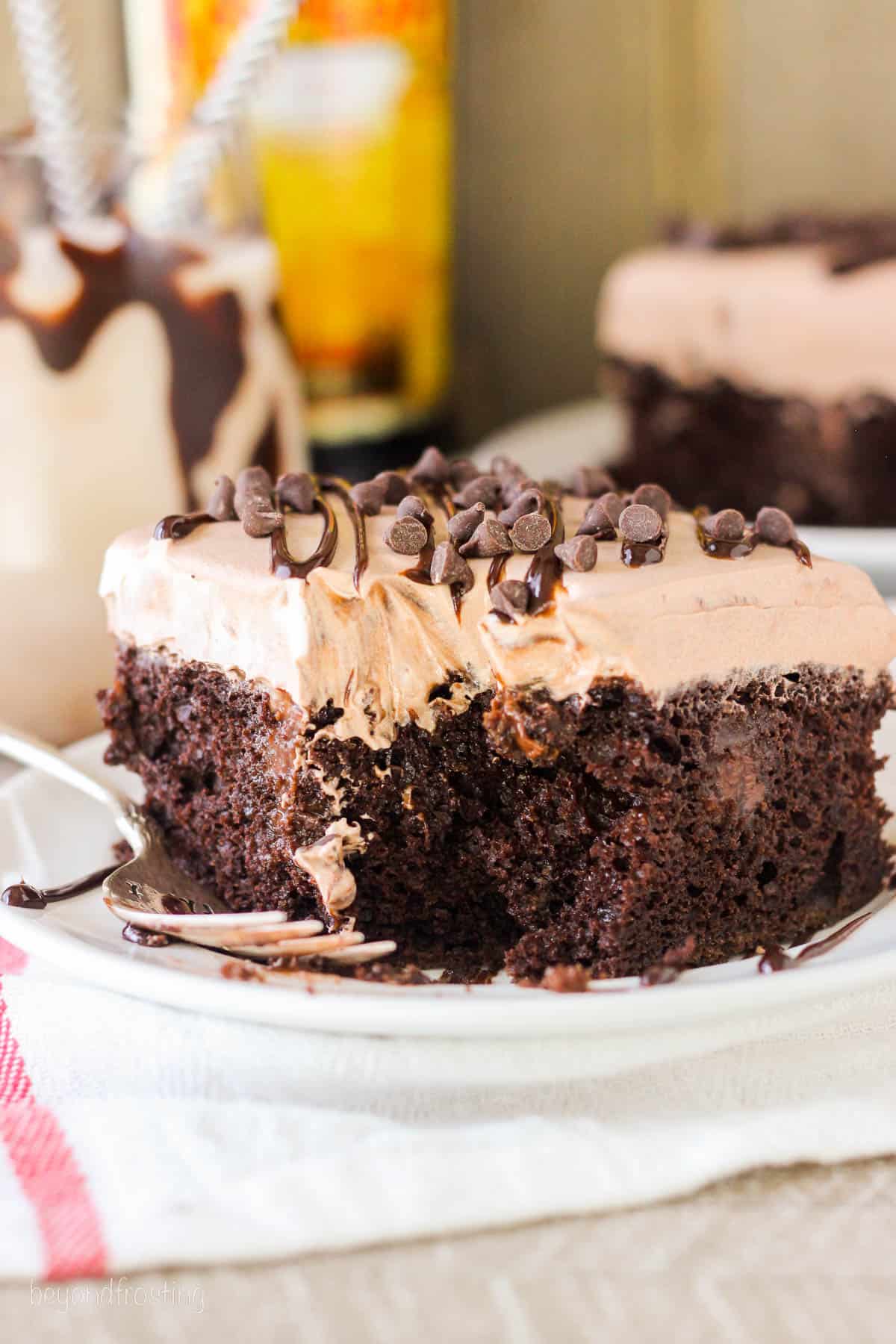 side view of a square slice of chocolate poke cake topped with chocolate chips.