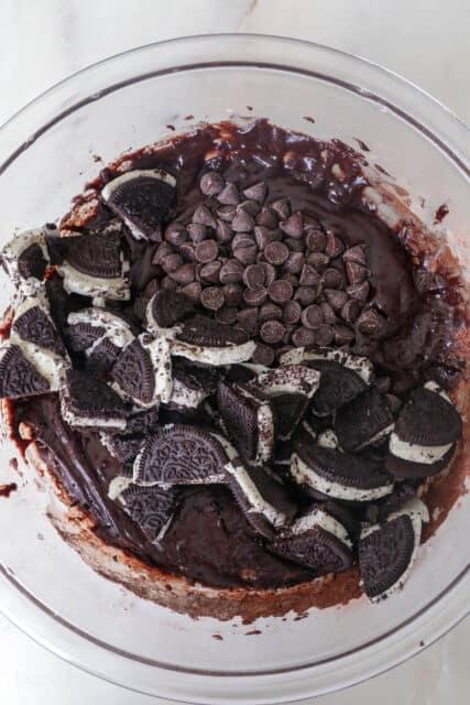 Chopped Oreos and chocolate chips added to a bowl of brownie batter.