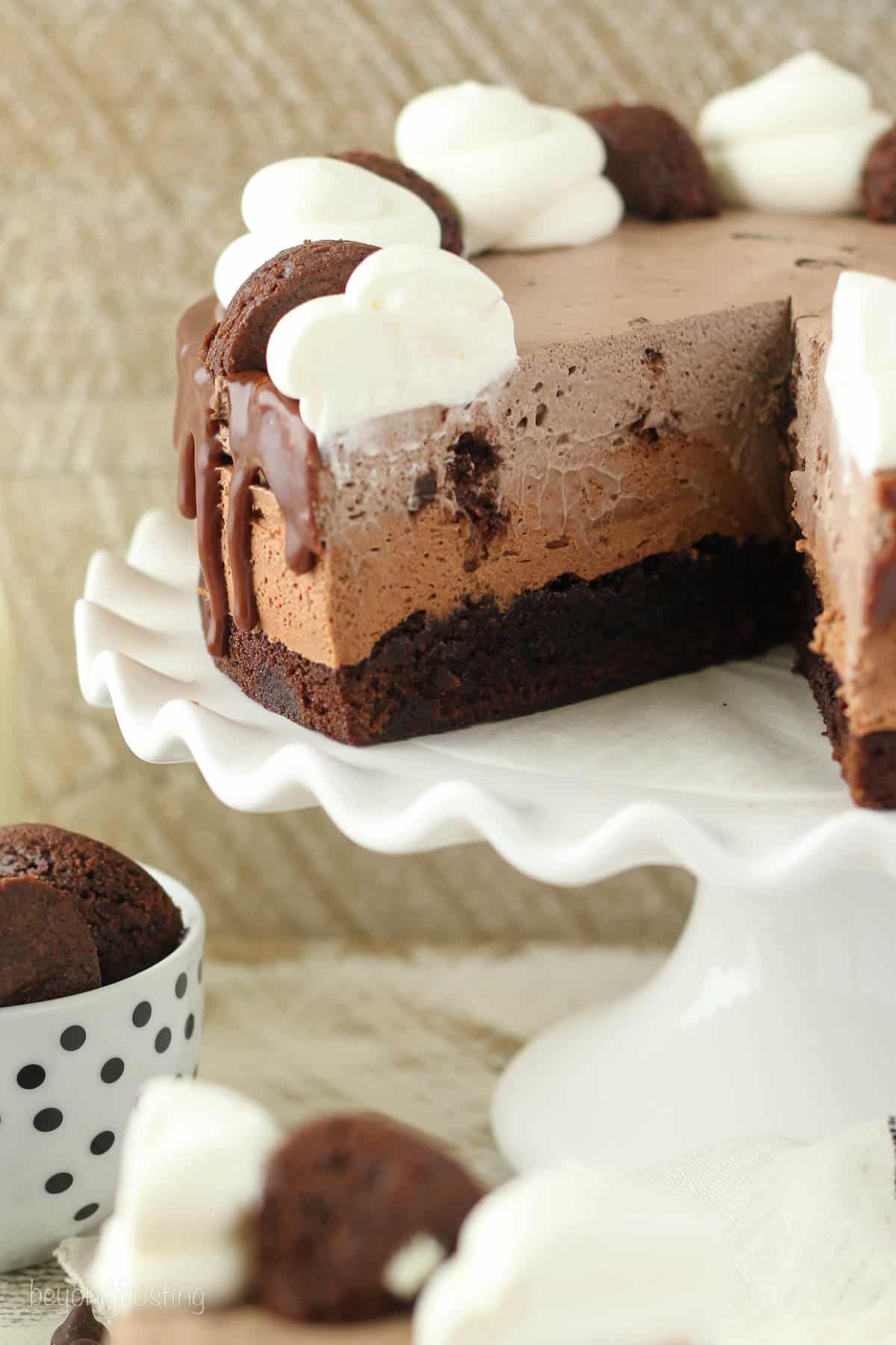a mousse cake on a cake stand with a slice cut out.