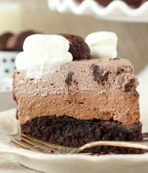 side view of a slice of mousse cake next to a fork on a plate.
