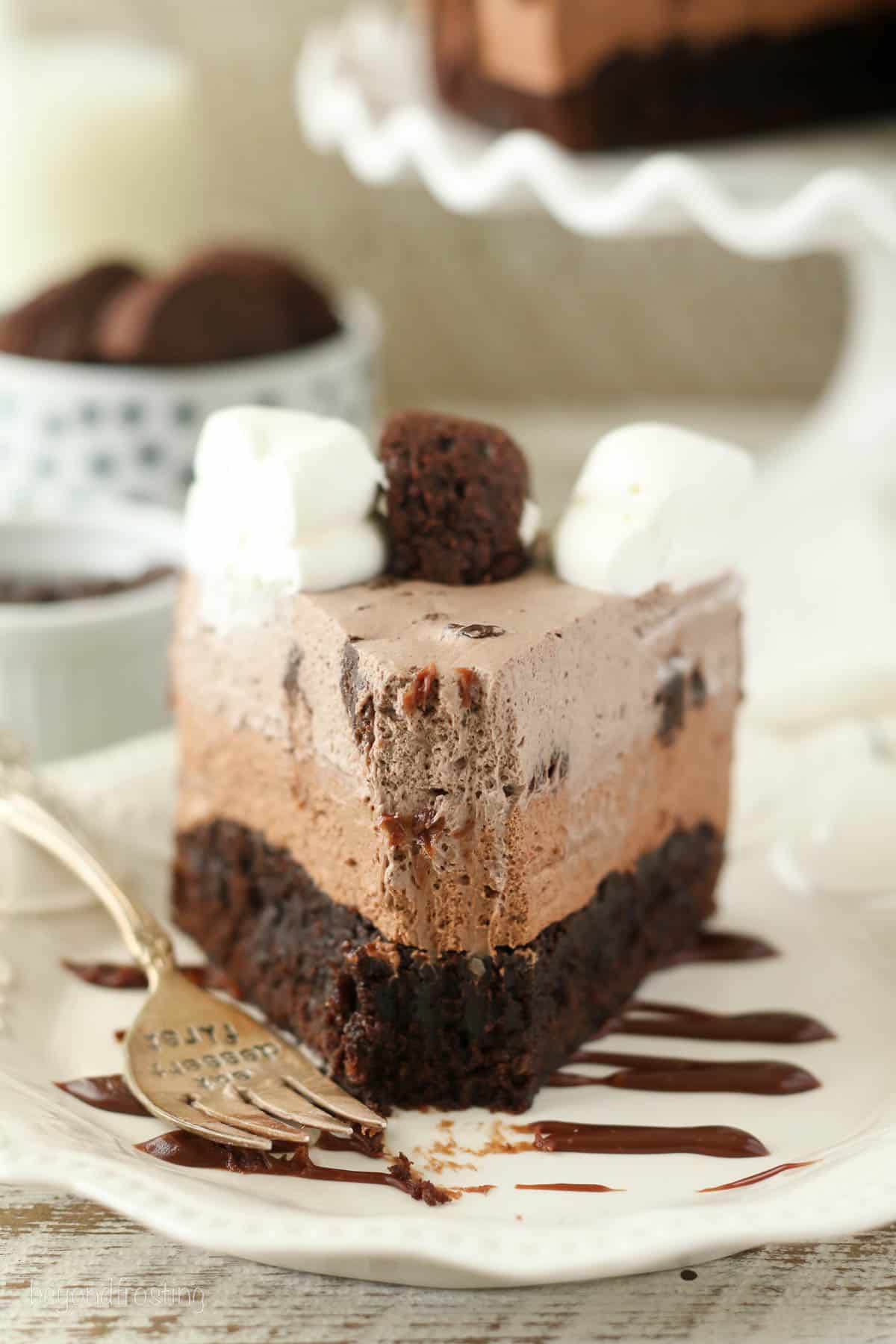 front view of a slice of chocolate mousse cake with a bite taken out.