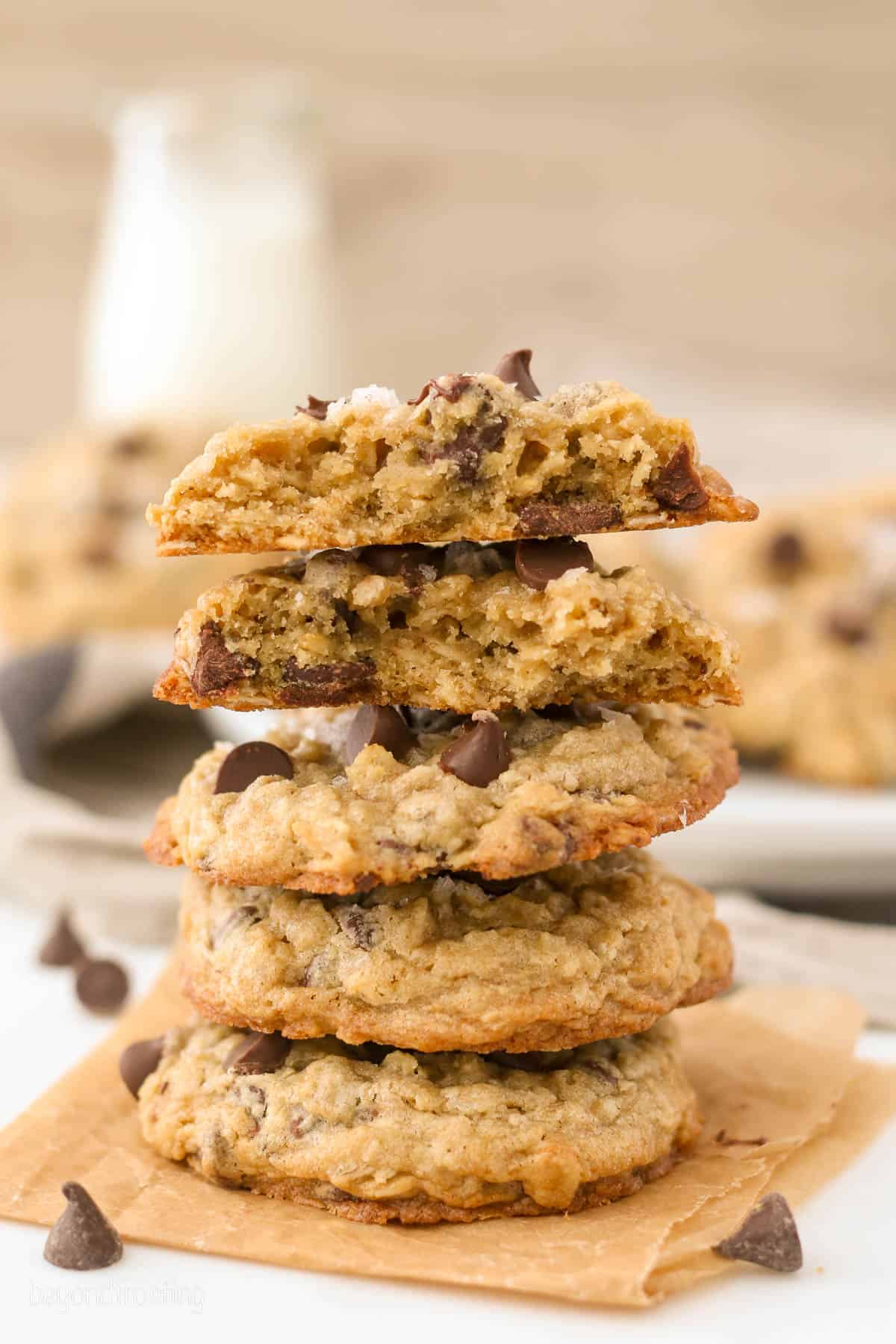 A stack of chewy chocolate chip oatmeal cookies on an orange napkin.