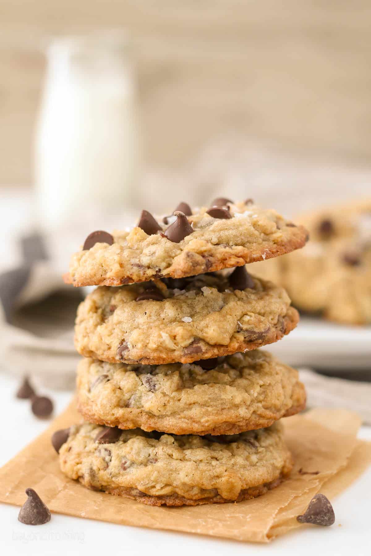 A stack of chewy chocolate chip oatmeal cookies on an orange napkin.