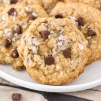 Chocolate chip oatmeal cookies topped with sea salt on a white plate.