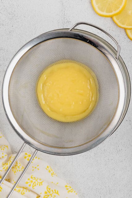 Finished lemon curd is strained through a fine mesh sieve.
