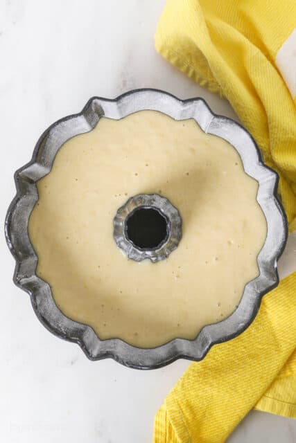 Lemon cake batter added to a greased and lined bundt pan.