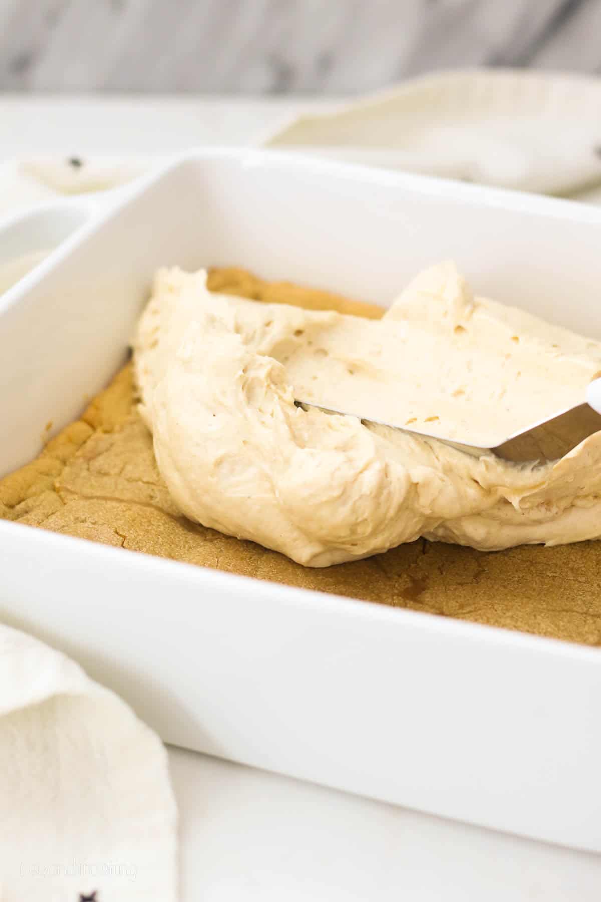 peanut butter cheesecake filling being layered over a cookie crust.