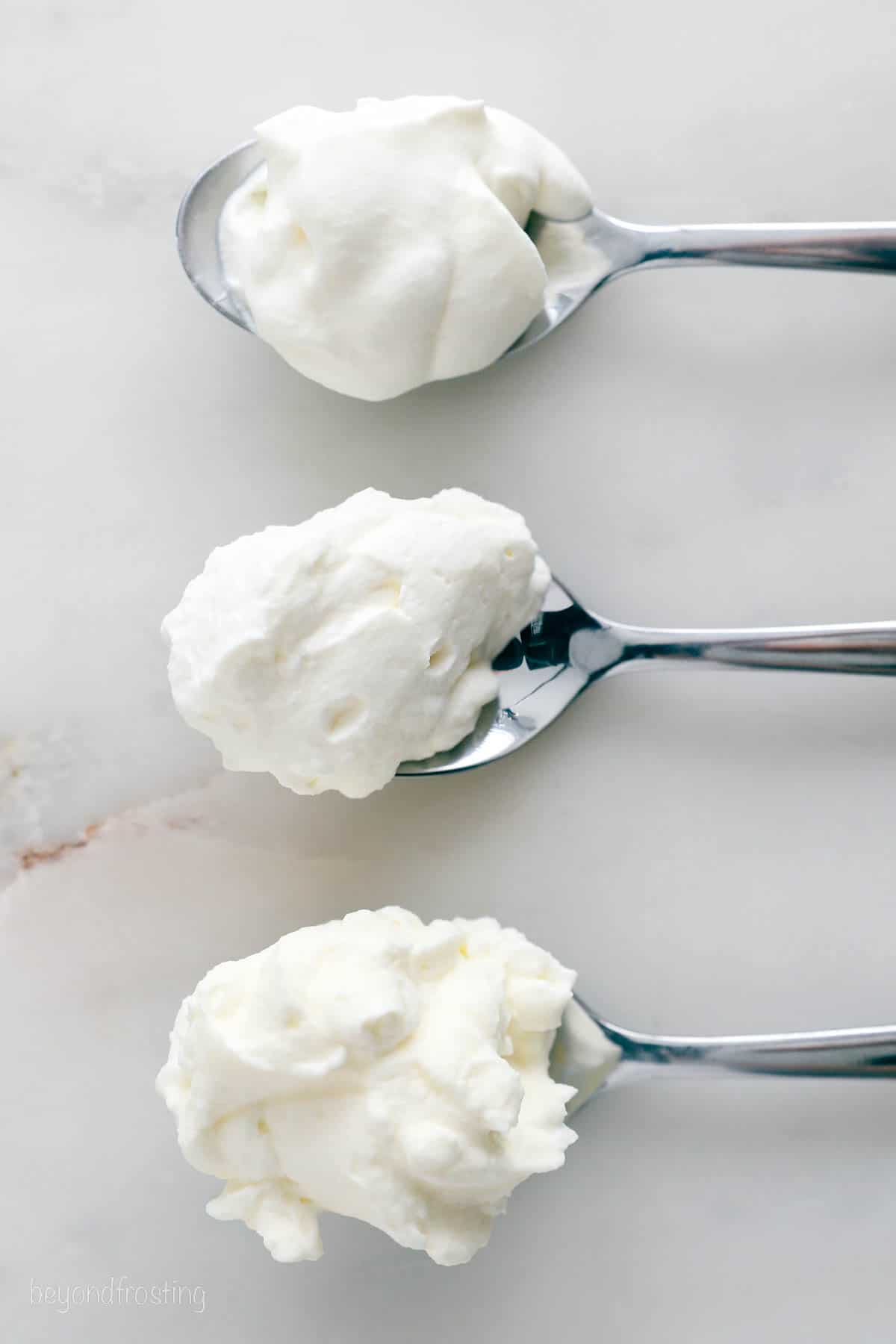 Three spoons showing the various stages of whipped cream, soft peaks, stiff peaks and overbeaten