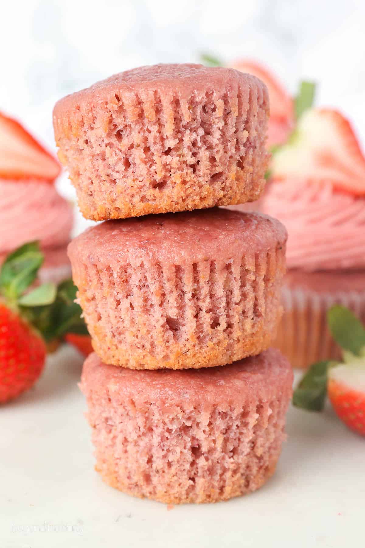 Three unfrosted strawberry cupcakes stacked on top of one another.