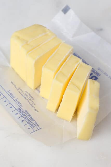 An unwrapped brick of cold butter cut into cubes.
