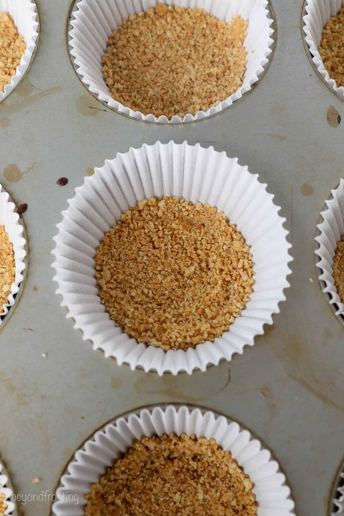 Overhead close-up view of cupcake liners with a graham cracker crust.