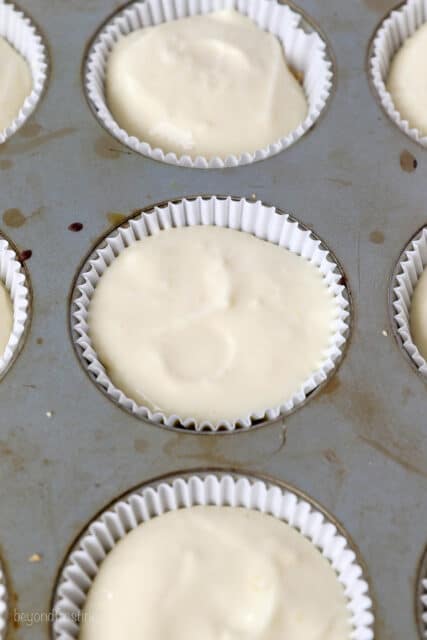 Close up of lemon cheesecake batter inside cupcake liners in a cupcake pan.