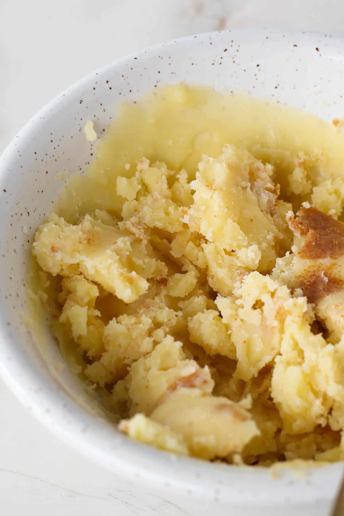 A white speckled bowl of solid brown butter