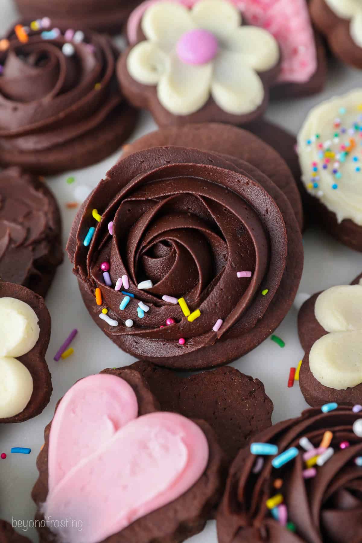 Close up overhead view of chocolate cutout sugar cookies frosted and decorated with various designs and buttercream colors.