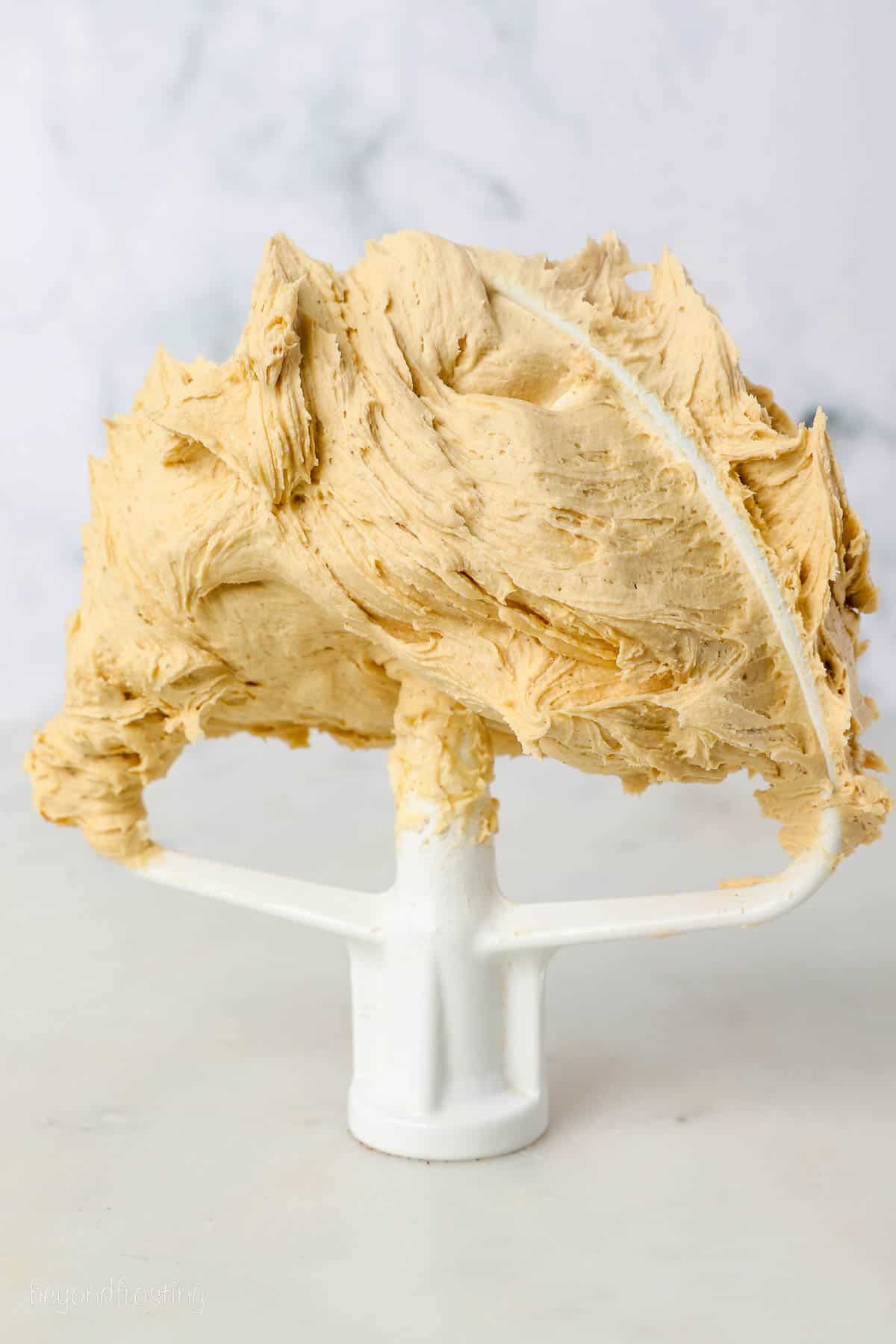 Coffee frosting on top of a stand mixer attachment propped up on a countertop.