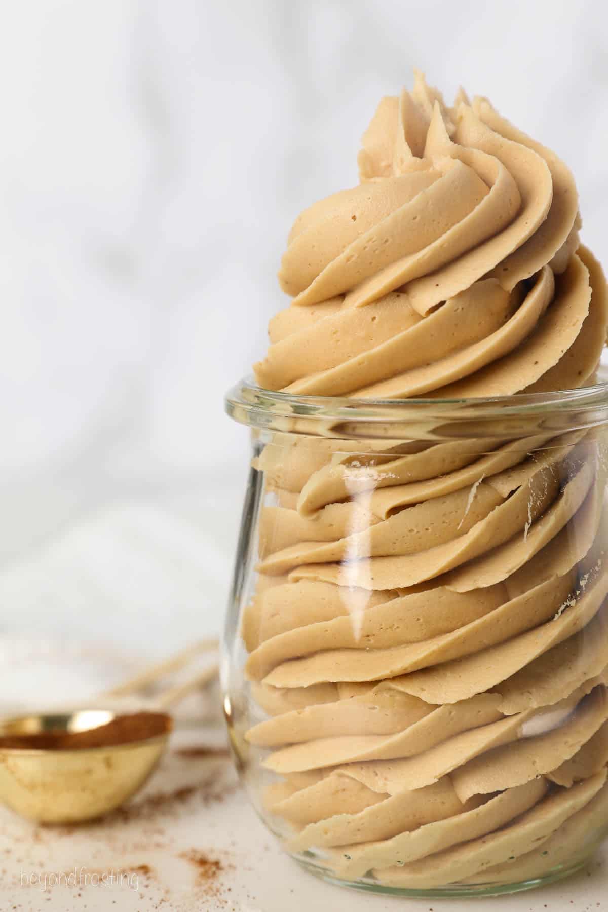 Close up of a swirl of coffee frosting piped into a glass jar.