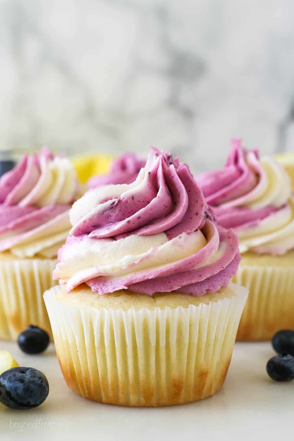 A close up of Lemon Blueberry Cupcakes with a swirled vanilla and blueberry buttercream