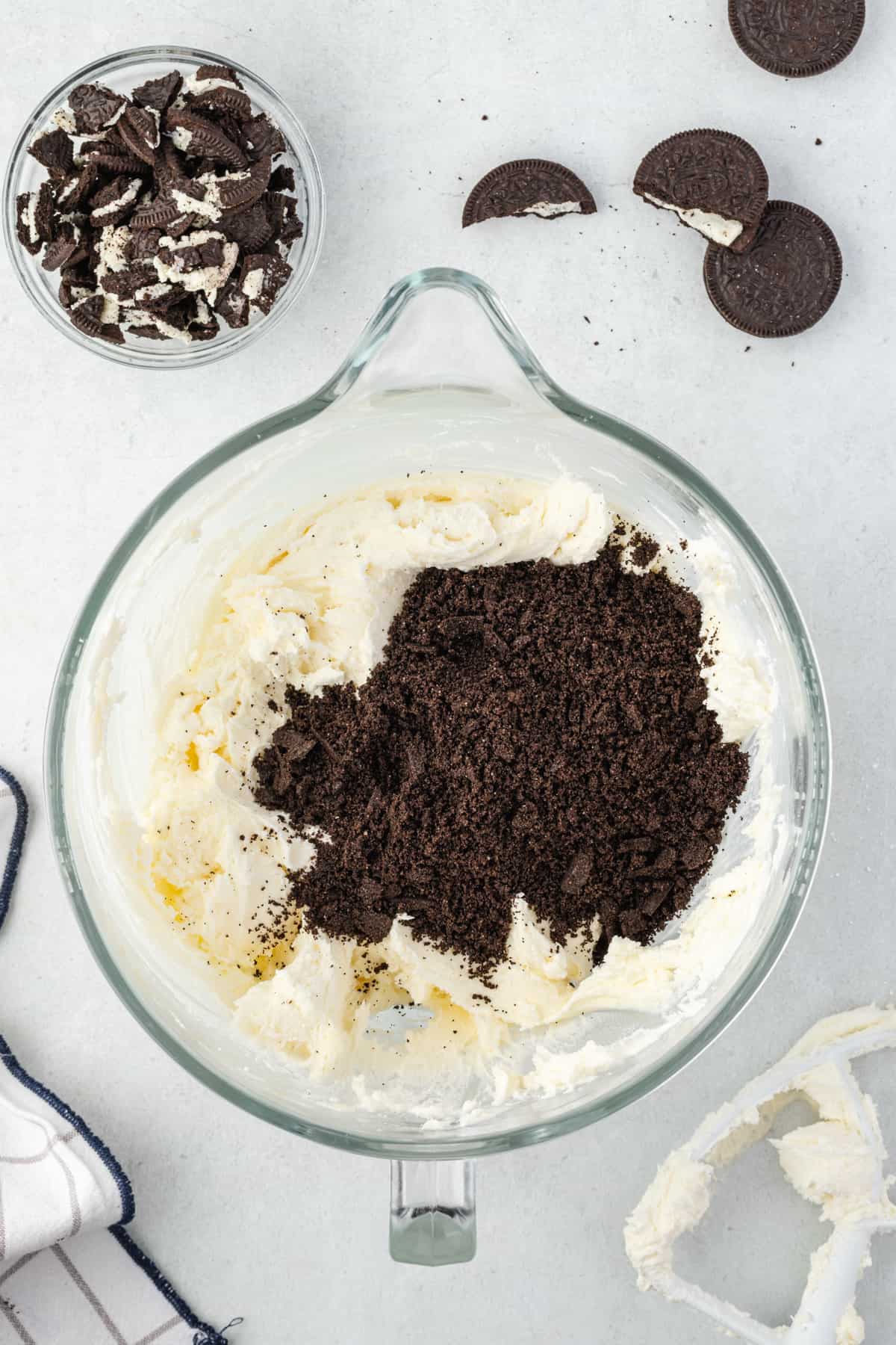 Crushed Oreo crumbs in a glass mixing bowl with vanilla buttercream
