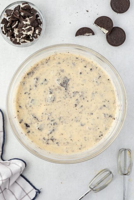 Batter for Oreo cupcakes in a glass bowl with whisk on the side