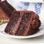 A slice of frosted chocolate zucchini cake laying on a plate.