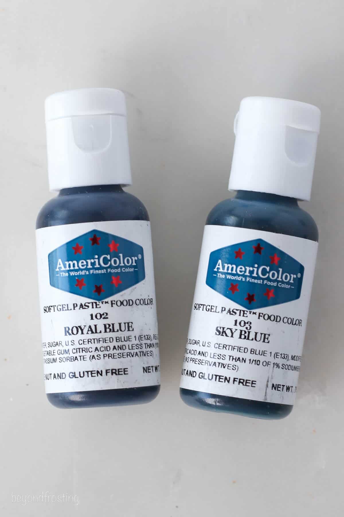 Two bottles of AmeriColor gel food dyes in Royal Blue and Sky Blue.