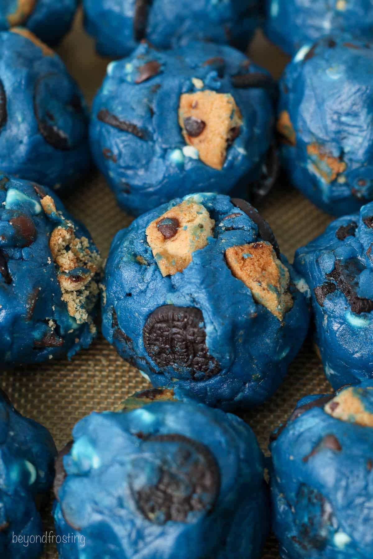 Close up of rolled Cookie Monster cookie dough balls on a baking sheet.