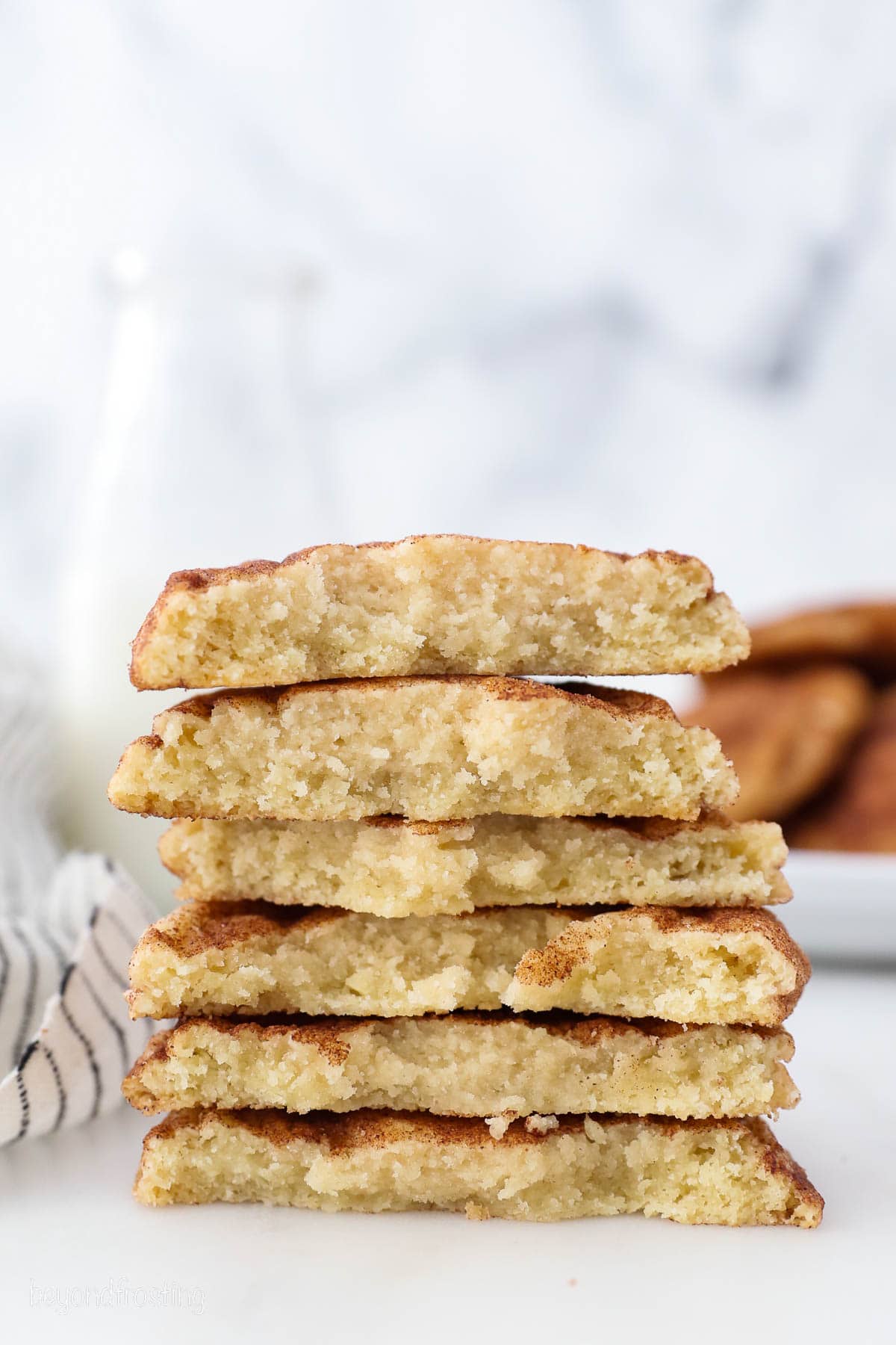 Snickerdoodle cookie halves stacked on top of one another on a white countertop.