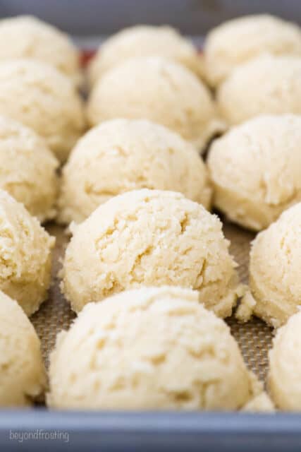Rows of scooped snickerdoodle cookie balls on a baking sheet.