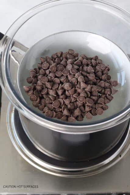 Chocolate chips in the glass bowl of a double boiler on the stovetop.