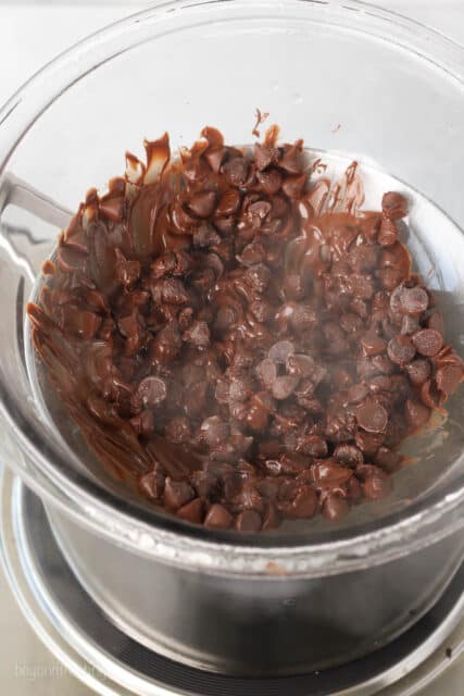 Chocolate chips melting in the glass bowl of a double boiler.