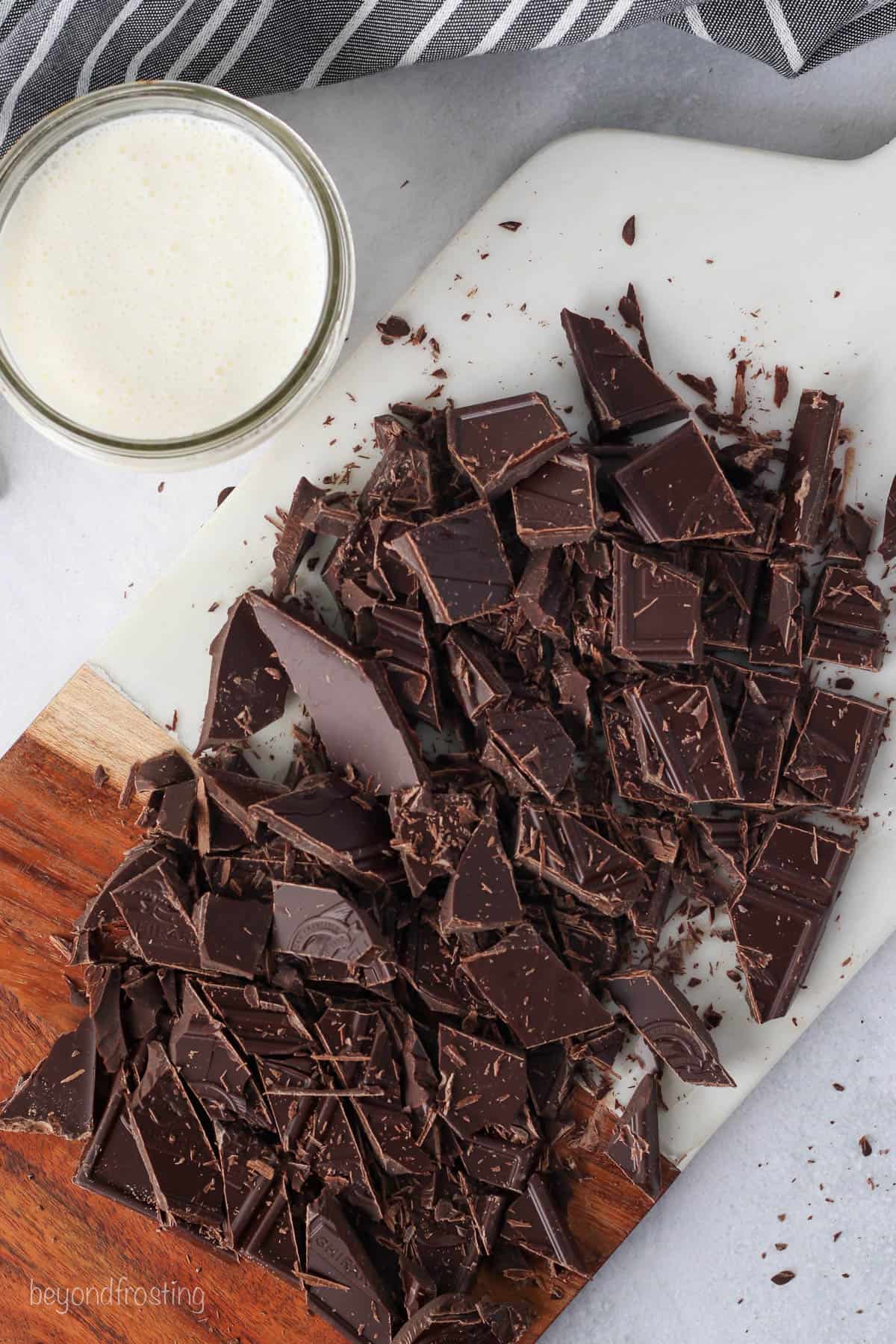 Overhead view of chopped chocolate next to a bowl of heavy cream.