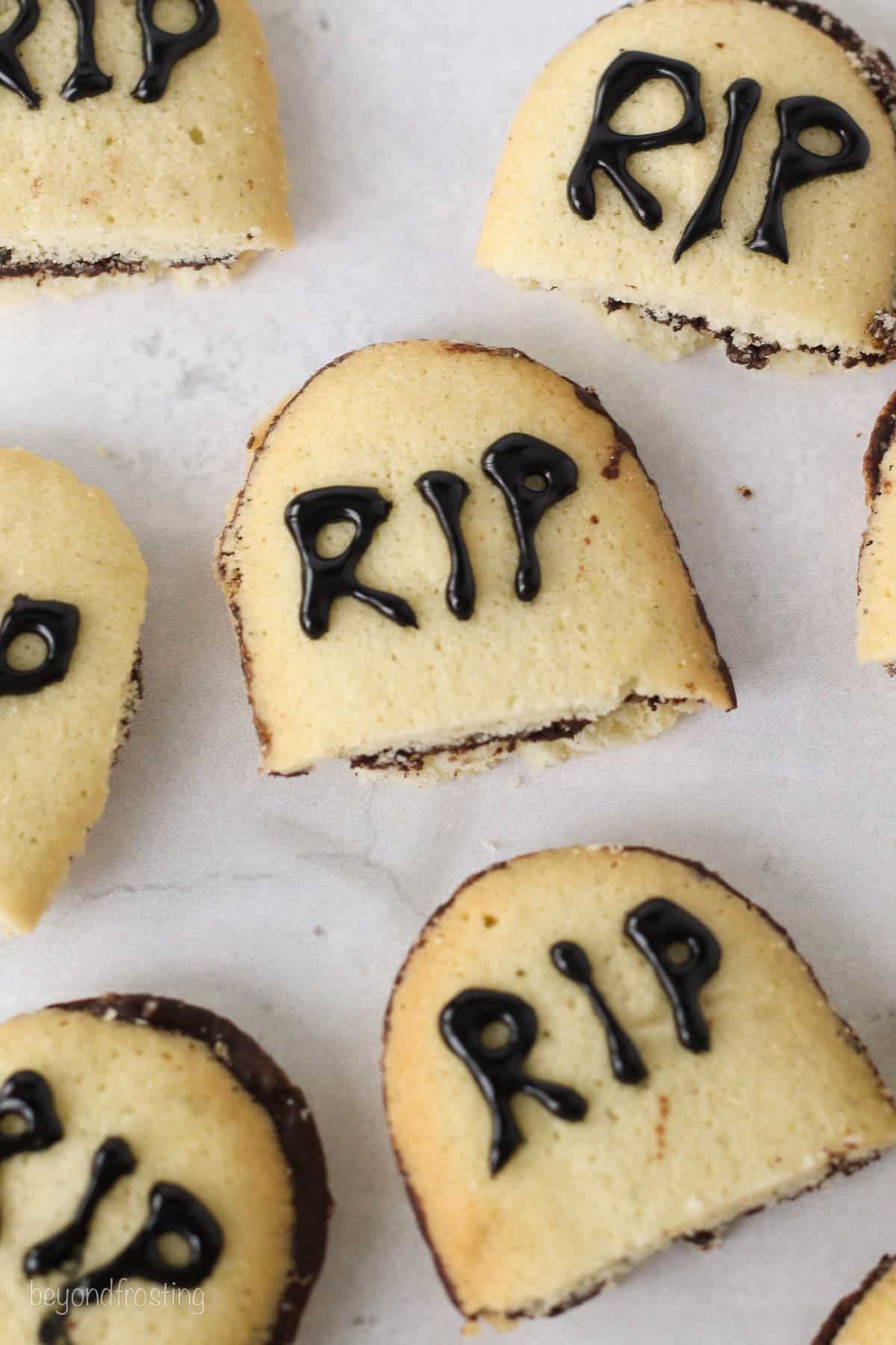 Close up of Milano cookies cut in half to resemble tombstones, decorated with "RIP" written in black gel icing.