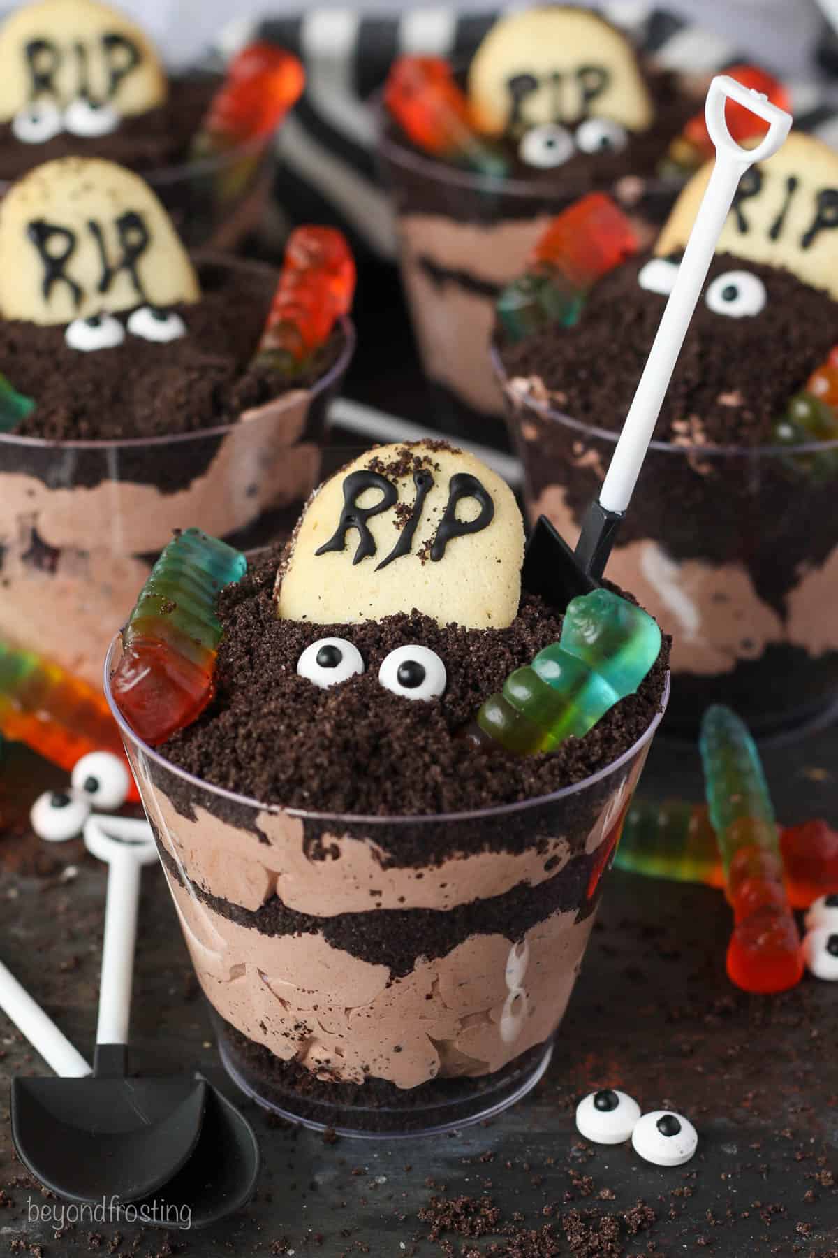 Assorted Halloween dirt cups decorated with Milano cookie headstones, candy eyes, and gummy worms.