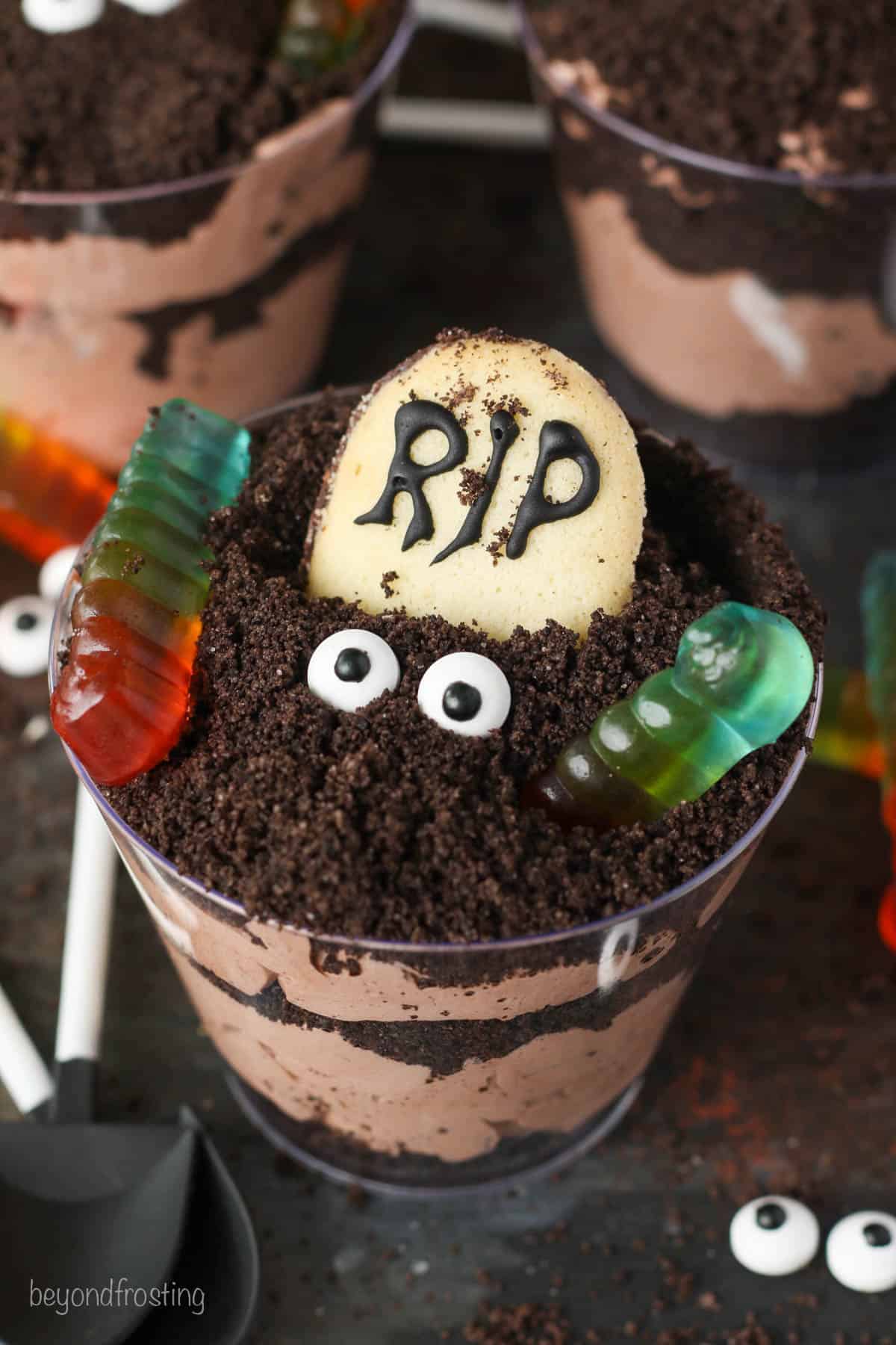 Close up of Halloween dirt cups decorated with Milano cookie headstones, candy eyes, and gummy worms.