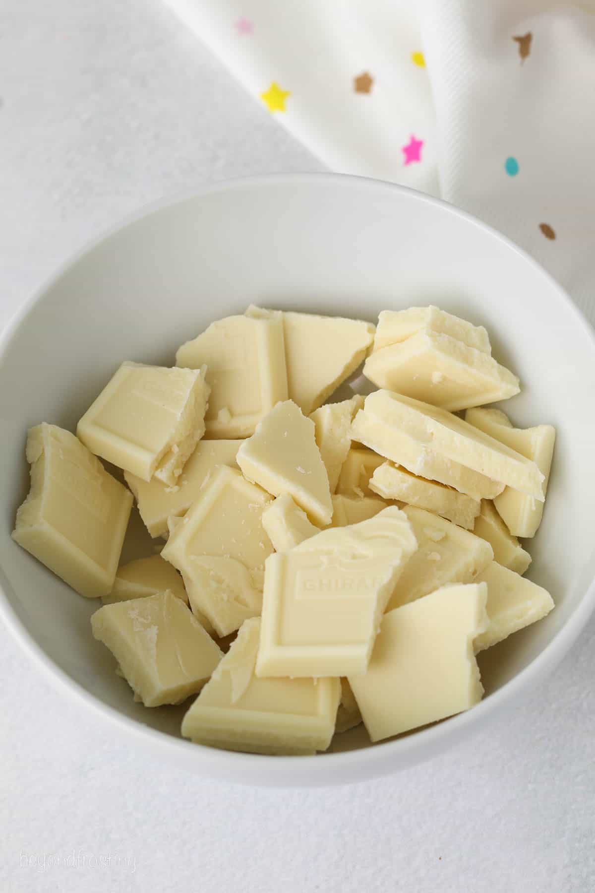 Chopped white chocolate in a white bowl.
