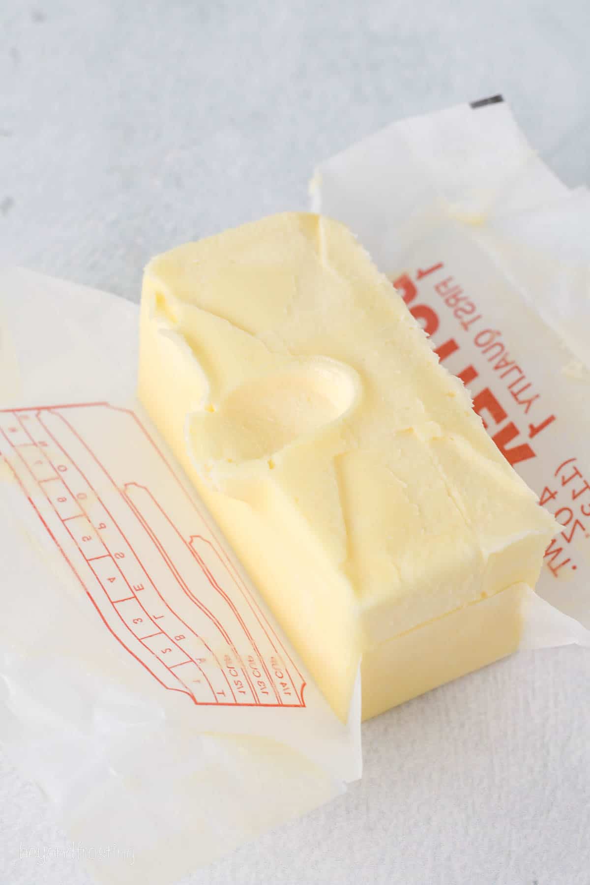 A brick of softened butter unwrapped on a countertop.