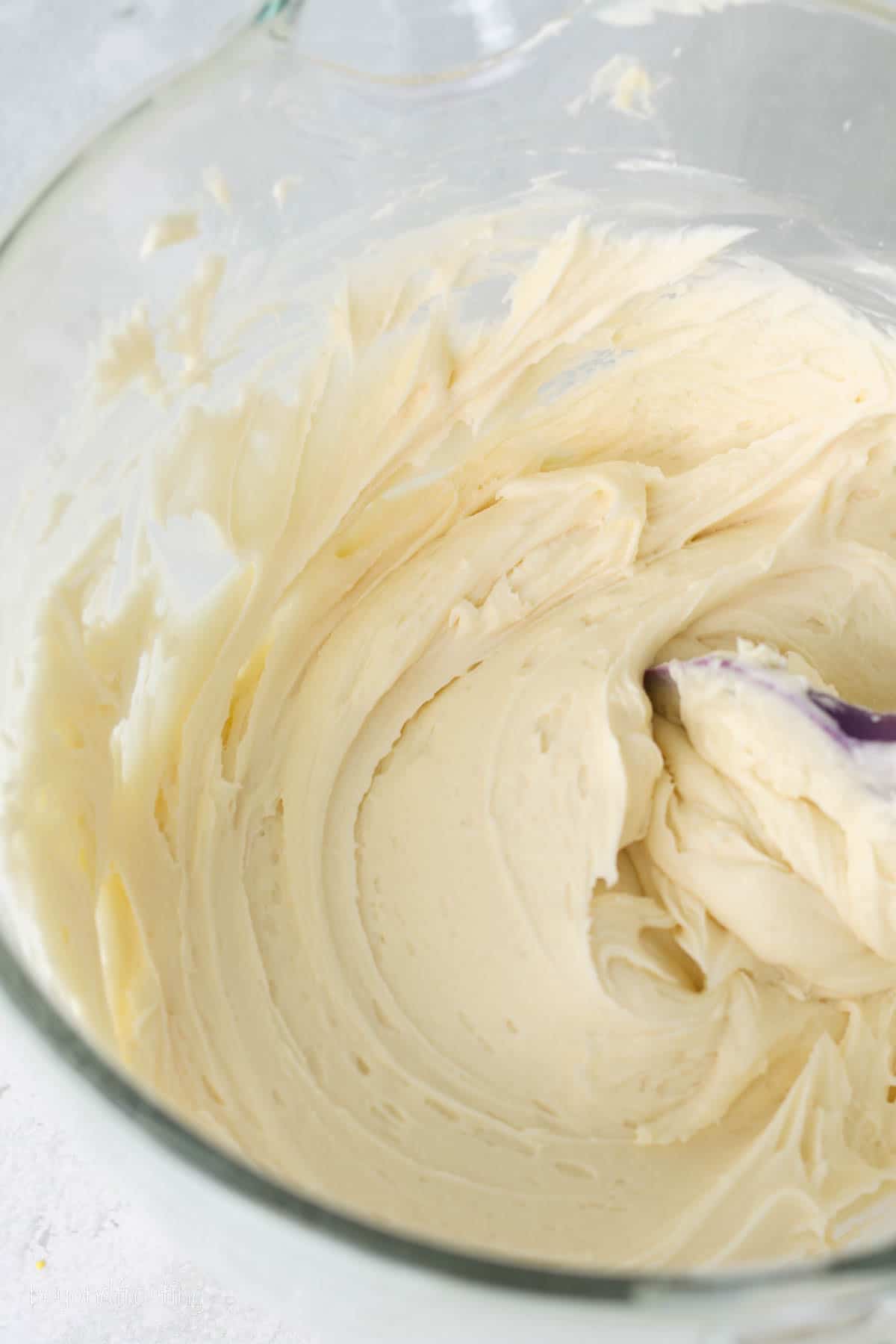 Whipped vanilla and cream cheese frosting in a glass bowl.