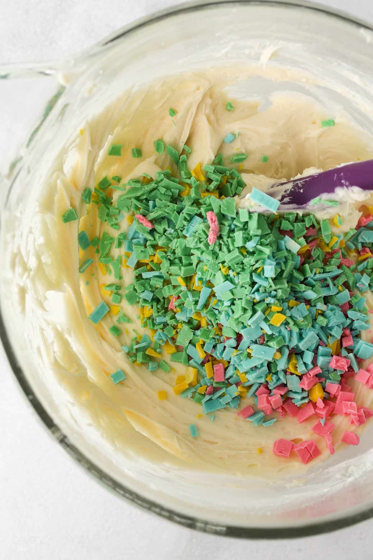 Rainbow chips added to a bowl of frosting.