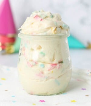 Rainbow chip frosting in a glass jar on a countertop.
