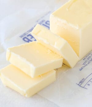 An unwrapped stick of butter sliced into squares.