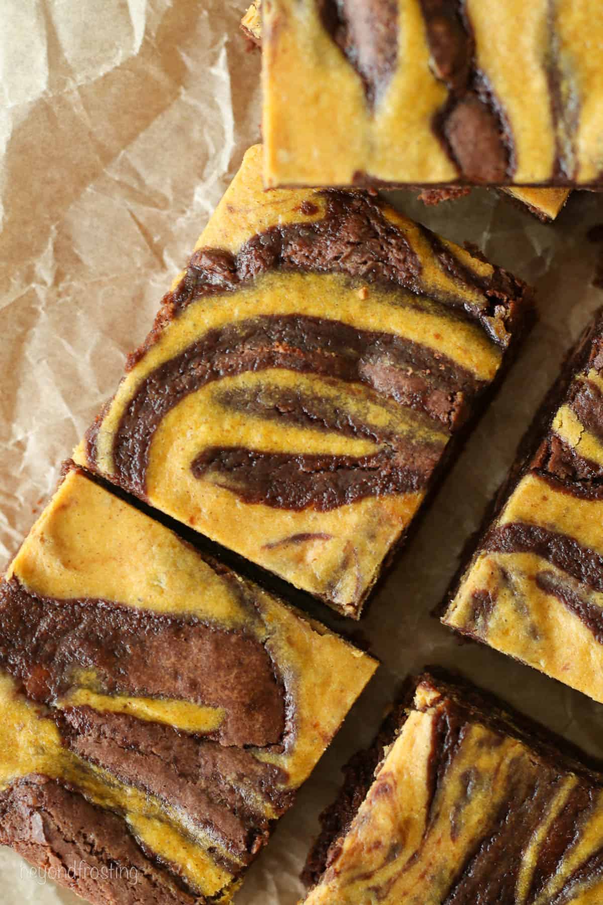 Close up of assorted pumpkin swirl brownies on a sheet of parchment paper.
