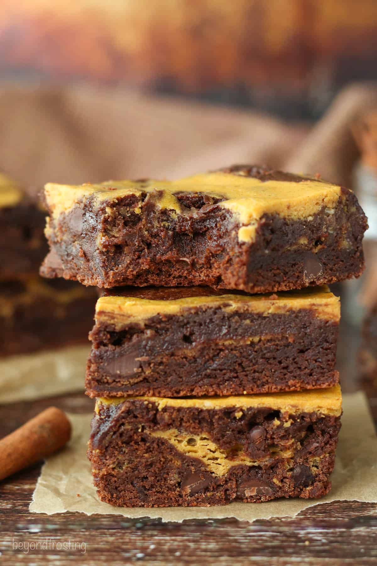 Three pumpkin swirl brownies stacked on top of one another.